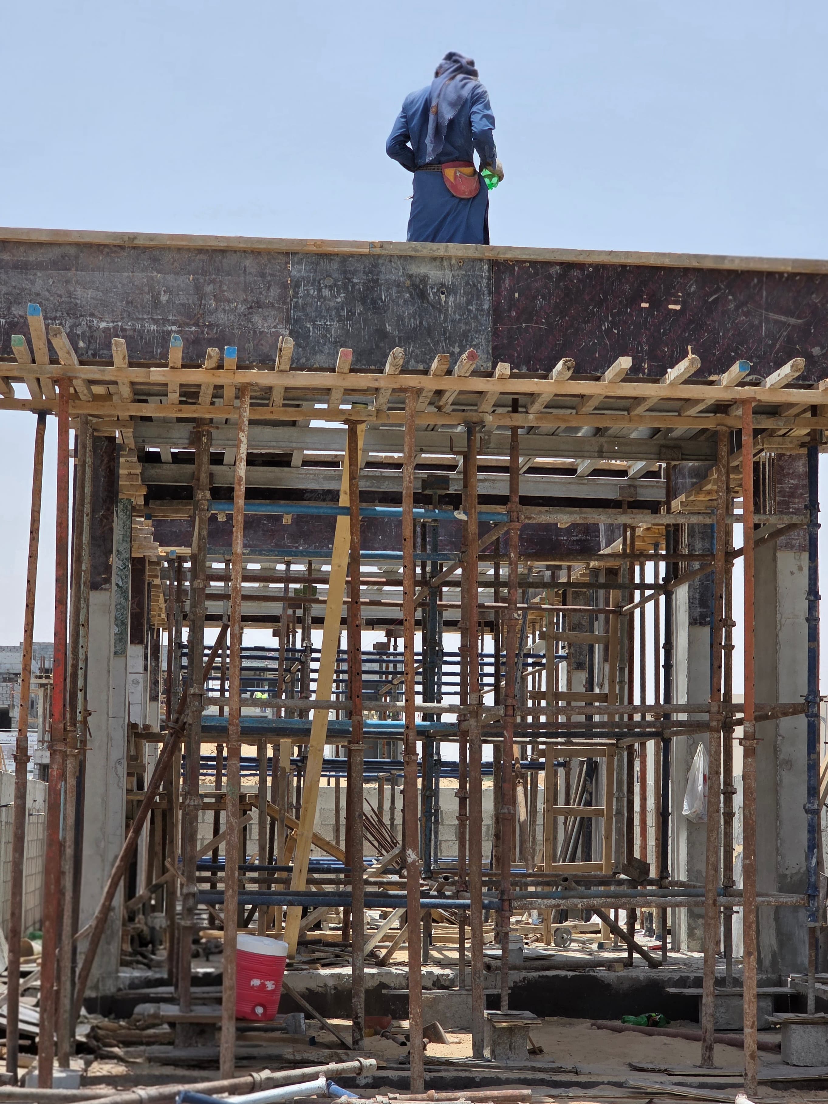 Worker installing propping and shoring system beneath a concrete slab on a construction site in Dubai